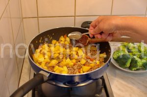 Мусака с кайма и броколи - поръсване с подправки